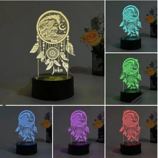 Black-based acrylic dream catcher table lamp with colourful LED lights on a wooden surface.