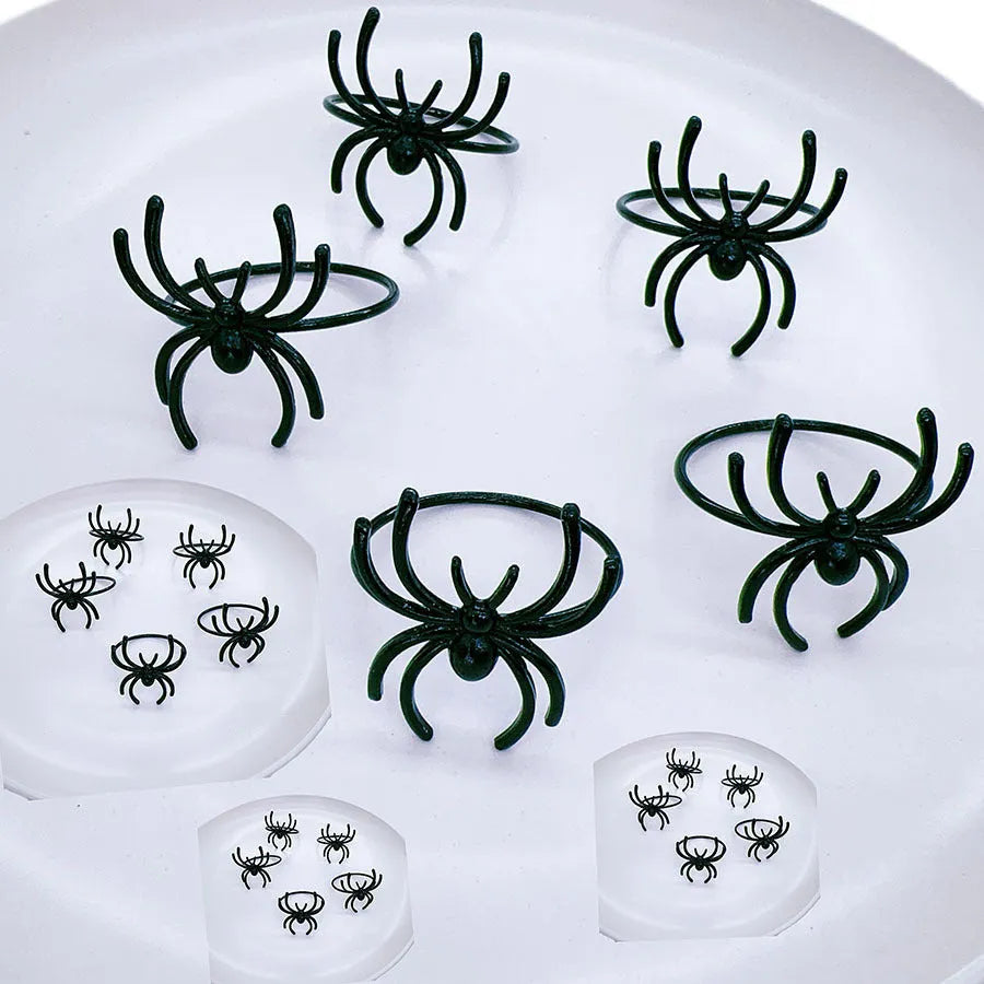Set of six black alloy napkin rings with detailed spider sculpture for Halloween table decor.