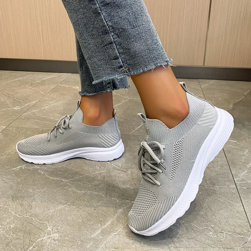 Women's low-top mesh running shoes in creamy white with a Flyknit upper and flat rubber sole.