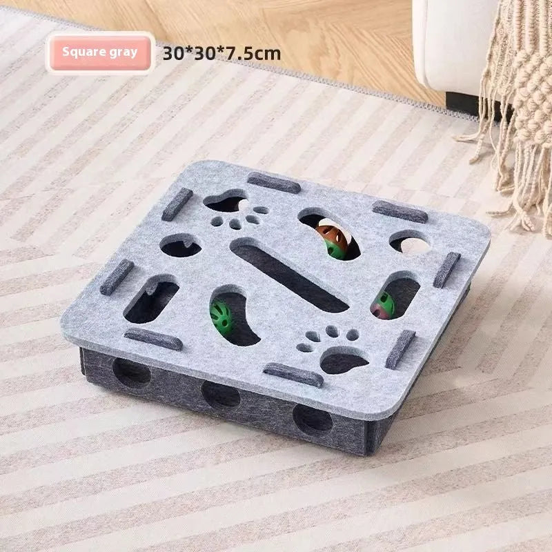 Square green brown felt cat puzzle box toy with a circular hole, shown next to a cat.