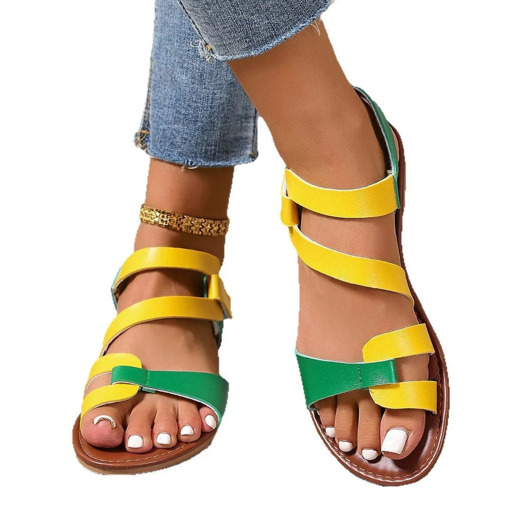 Women's flat sandals with Velcro strap, round toe, and rubber sole in black, brown, and colourful options.
