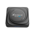 Black Android TV set-top box with HDMI port, shown with remote control and UK plug power adapter.