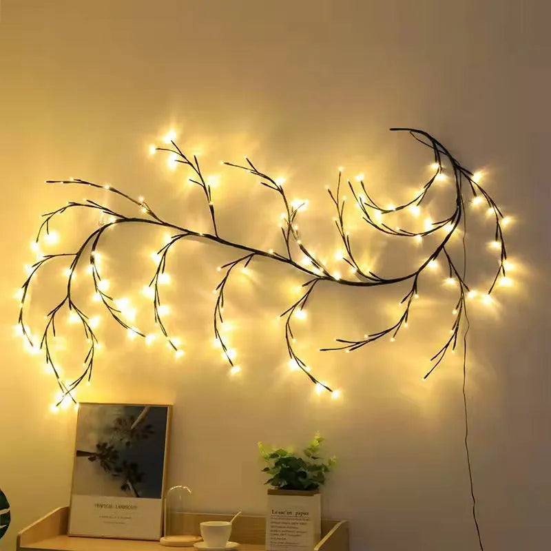 Flexible plastic LED willow vine garland with warm white lights bent into a decorative shape on a wall.