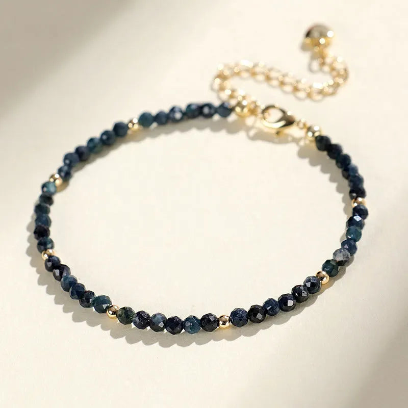 Blue tourmaline gemstone bracelet with 3mm cut beads on a white background.