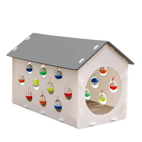 White plastic house-shaped cat scratch board with sisal siding, an arched tunnel entrance, and a dangling red bell ball toy.