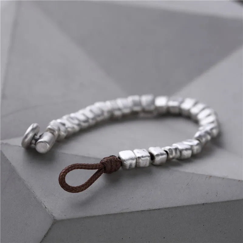 Handmade women's bracelet with an irregular silver square pendant on a wooden elastic band.