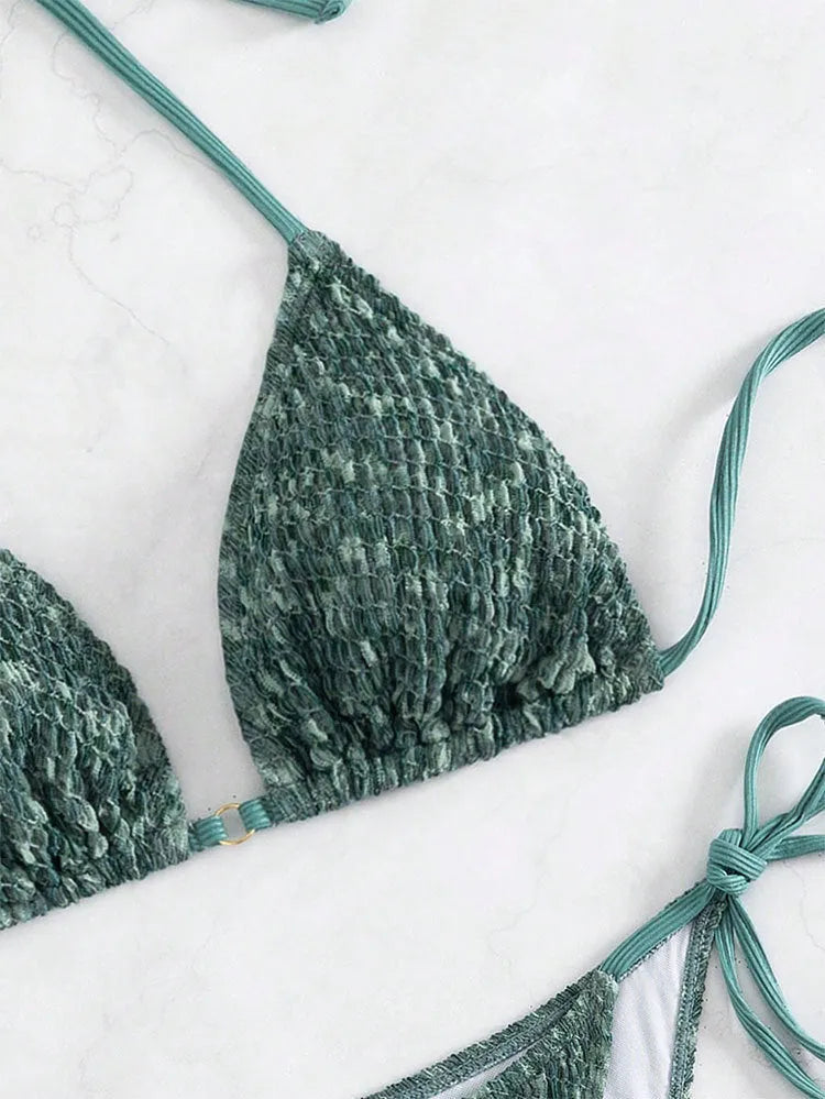 Green backless women's bikini with halter neck strap lying flat.