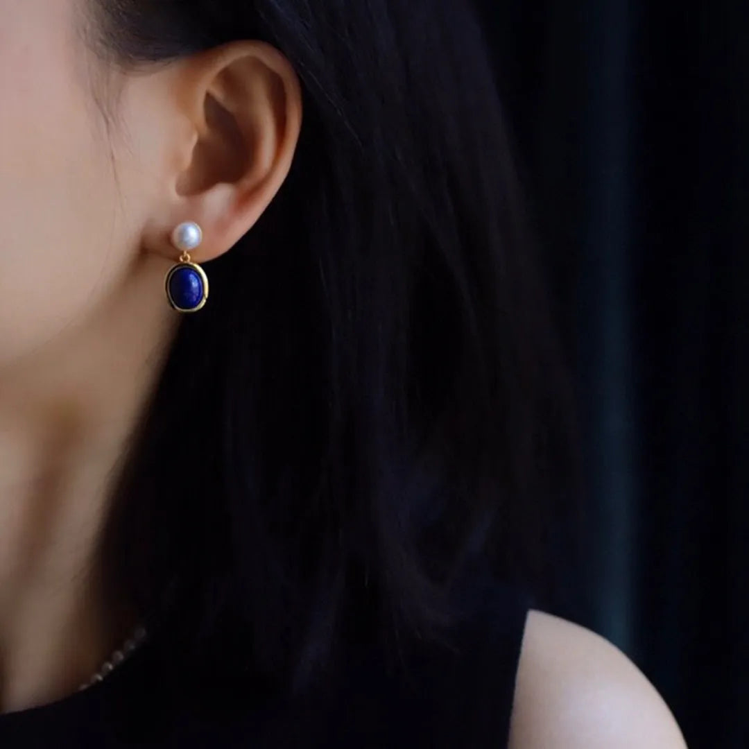 A pair of simple sterling silver earrings featuring deep blue lapis lazuli pearls.