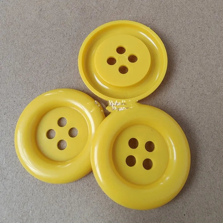 Oversized round edge plastic button with four holes in various colours and diameter sizes