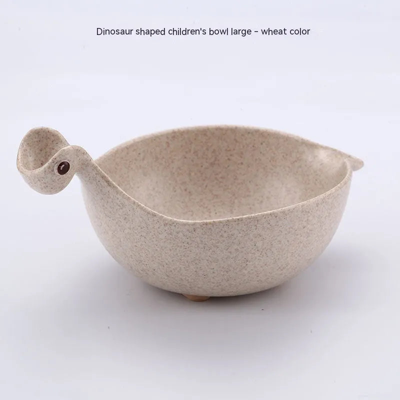Three wheat straw dinosaur bowls in pink, green, and beige on a kitchen table