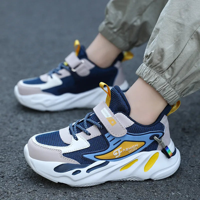 Boy's blue sports running shoe with velcro strap and mesh upper on a hard ground surface.