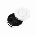 Mini black semi-in-ear wireless headphones with their compact wireless charging case on a table.