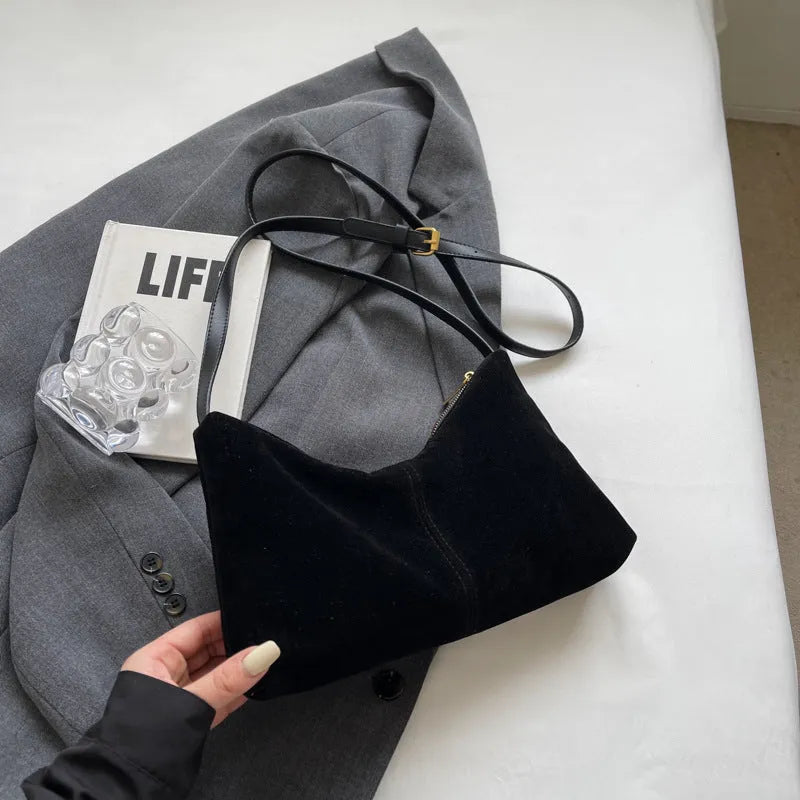 Retro brown suede underarm bucket bag with visible sewing line detail on a woman's shoulder during commute