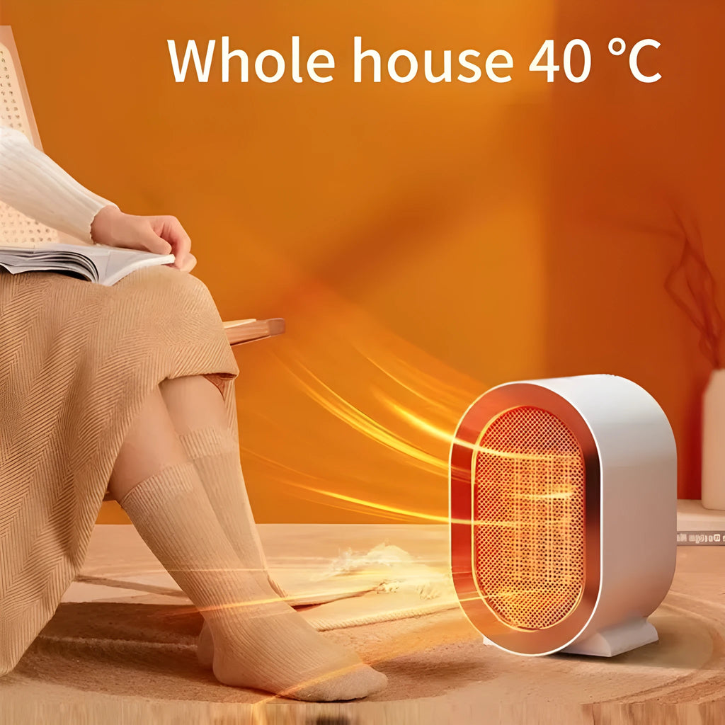 A compact black desktop electric fan heater with mechanical control dials on a wooden desk.