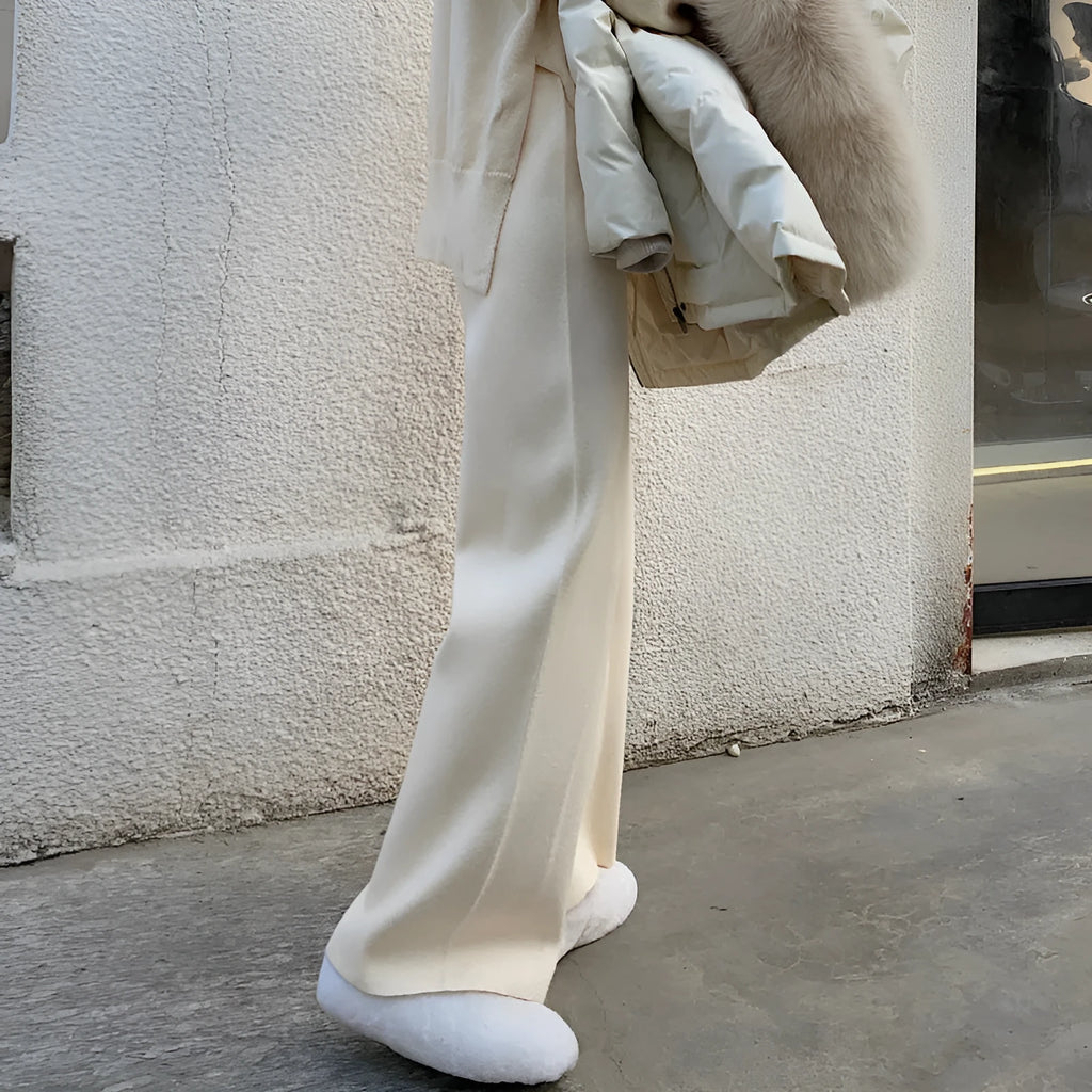 Women's high-waisted knitted wide-leg trousers in black, shown in a casual setting.