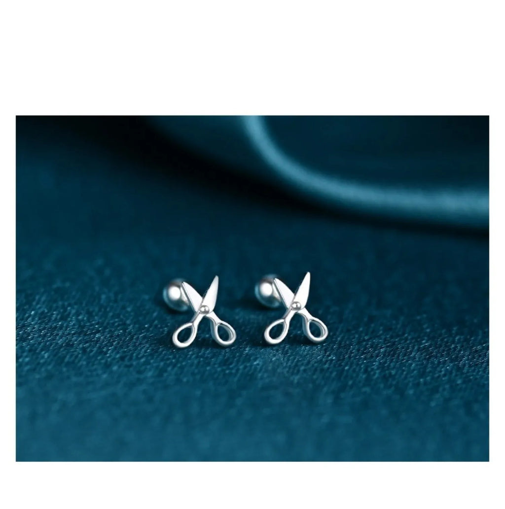 A pair of screw-back earrings made from 999 pure silver with a miniature silver scissors charm.