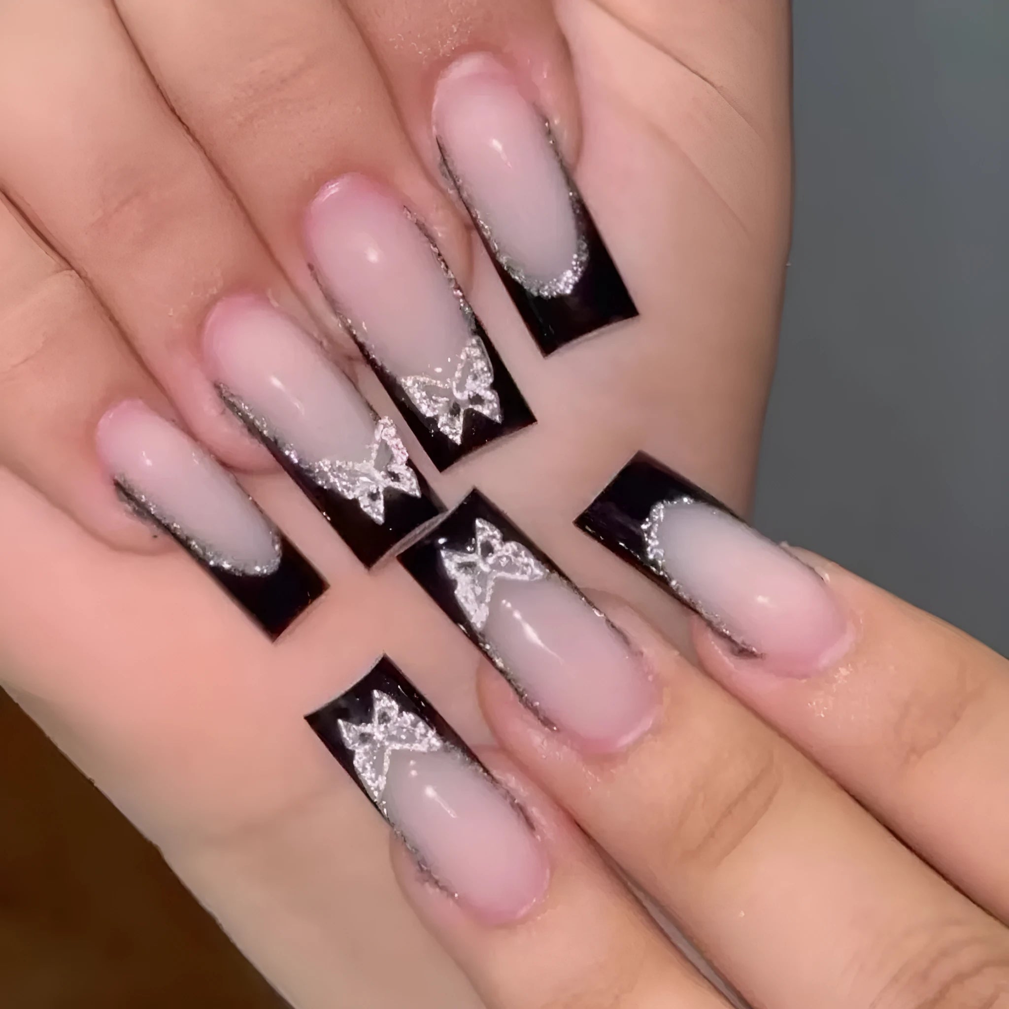 Black French style artificial nails with glitter butterfly design in medium length