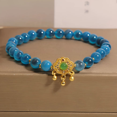 Blue sugar heart agate safety lock pendant on women's bracelet with alloy inlay and crystal accents.