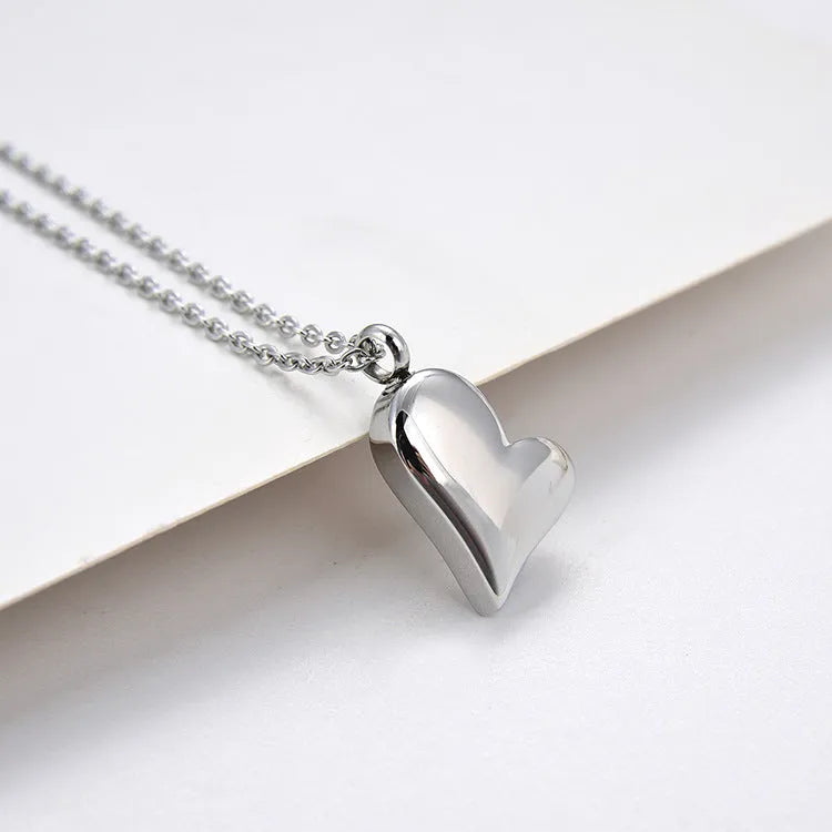 Silver curved peach heart pendant on a stainless steel necklace with an extension chain.