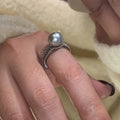 Geometric copper adjustable ring with a black pearl for women, shown on an index finger.