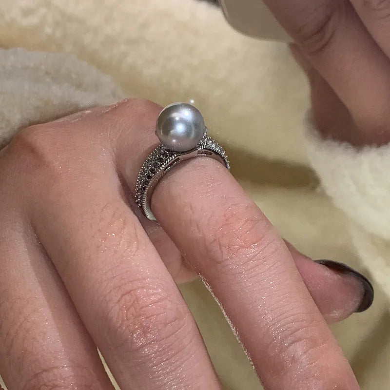 Geometric copper adjustable ring with a black pearl for women, shown on an index finger.