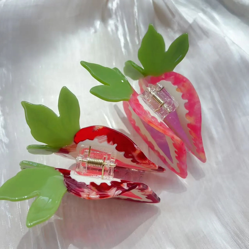 Red and pink strawberry-shaped metal charm hair clip for girls on a white background.