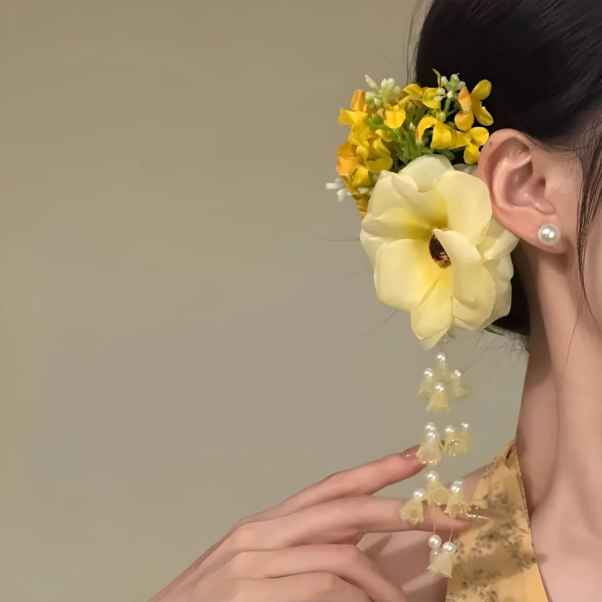 Handmade yellow and purple floral hair clip with pearl beads and long tassels on a metal side-clip.