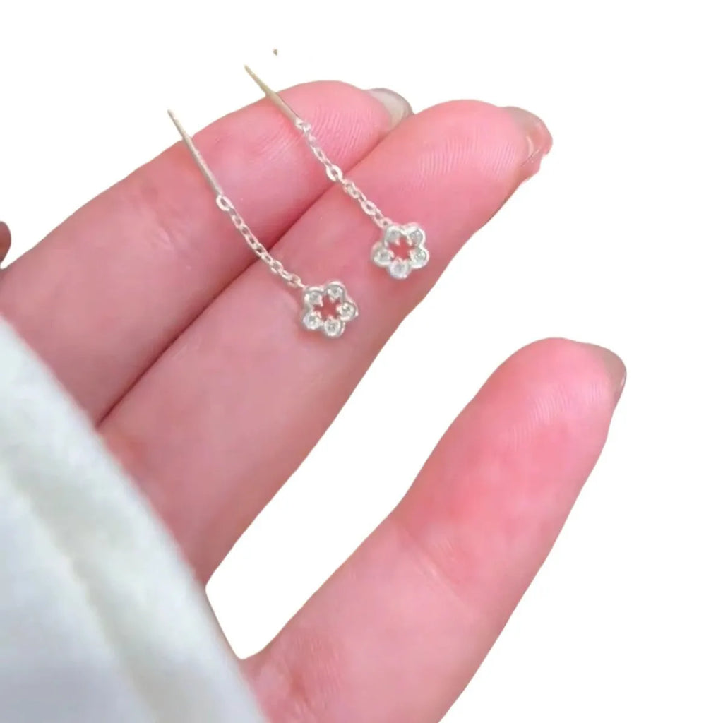 A pair of silver-colour alloy drop earrings featuring a detailed hollow flower design with visible petals.
