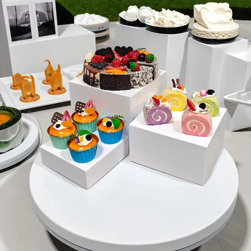 Six white geometric cube dessert display stands arranged on a table.