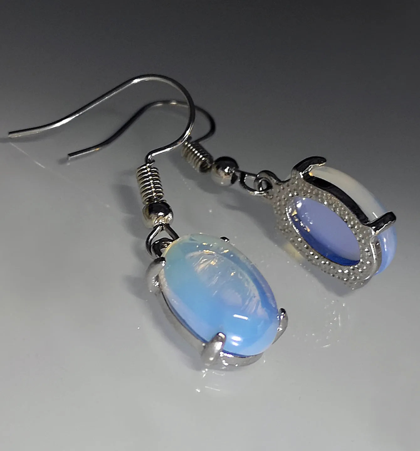 A pair of white opal-coloured drop earrings with a retro cross design on an alloy pendant.