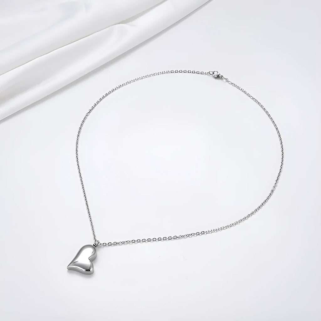 Silver curved peach heart pendant on a stainless steel necklace with an extension chain.