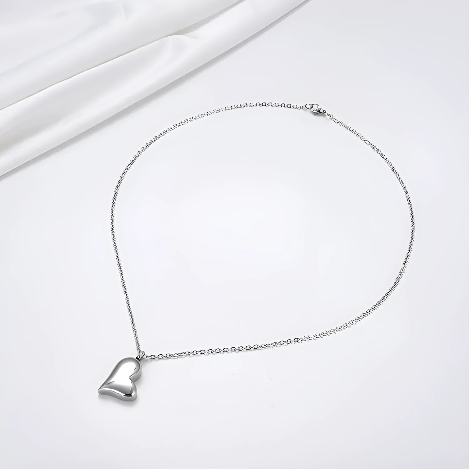 Silver curved peach heart pendant on a stainless steel necklace with an extension chain.