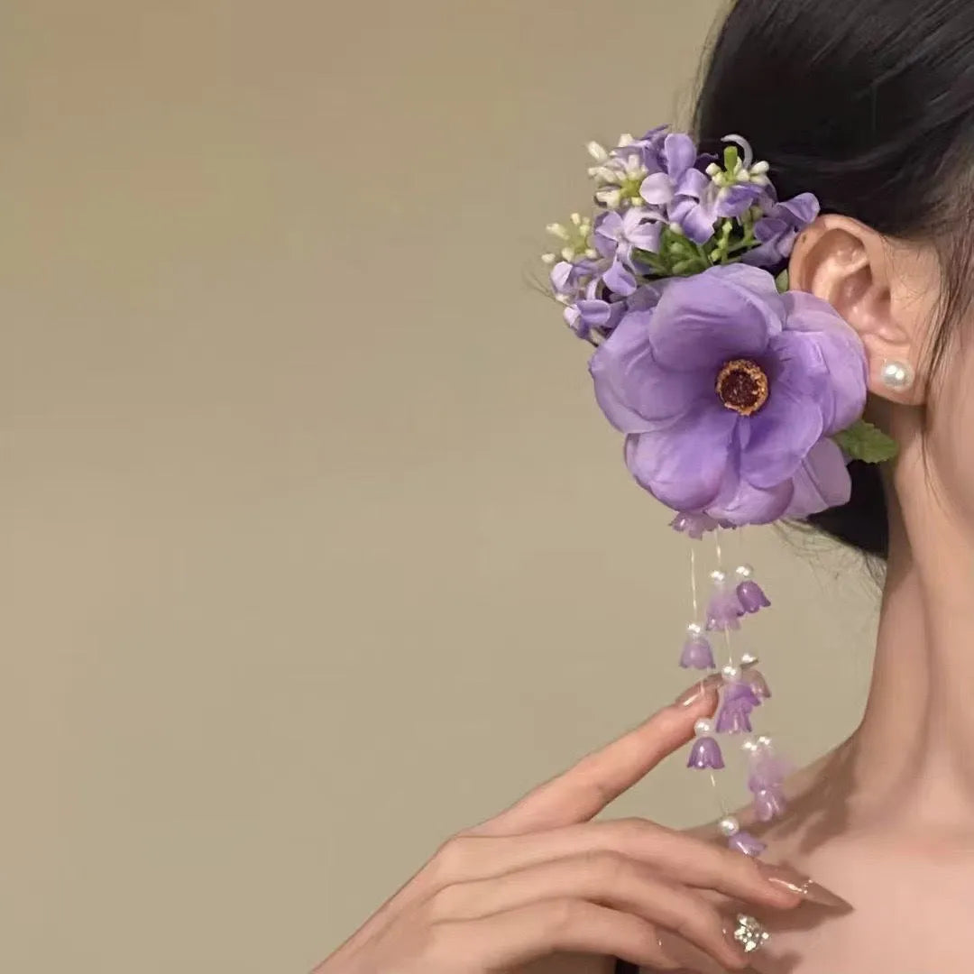Handmade yellow and purple floral hair clip with pearl beads and long tassels on a metal side-clip.