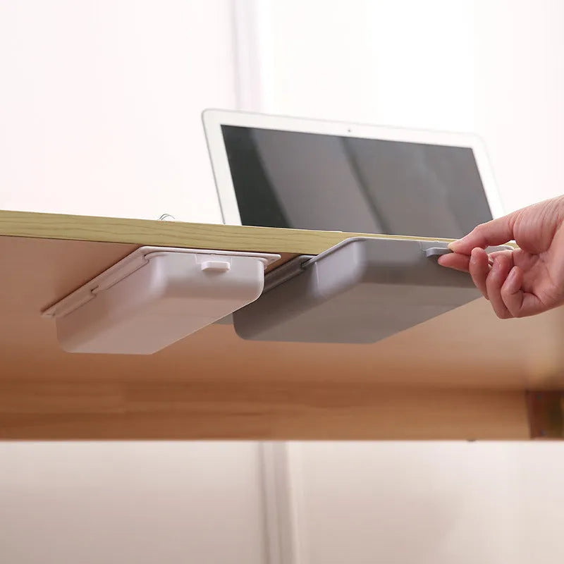 White plastic storage drawer with a cover and internal grid compartments, shown mounted underneath a wooden table.