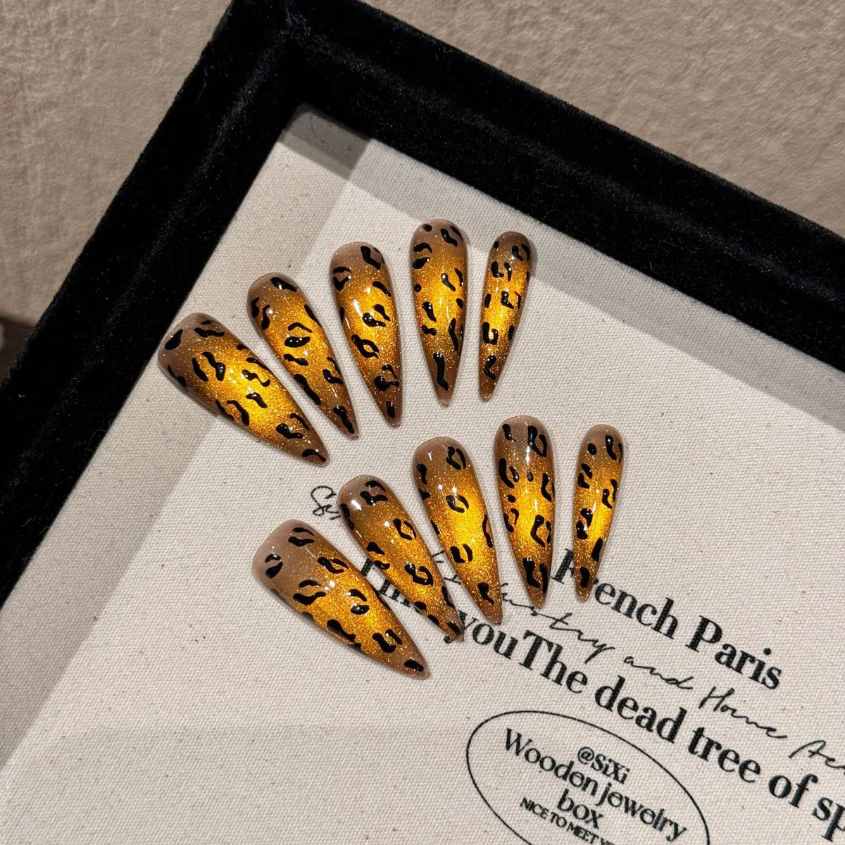 Handmade false nails with tiger pattern, leopard print and white base in a cat eye shape.