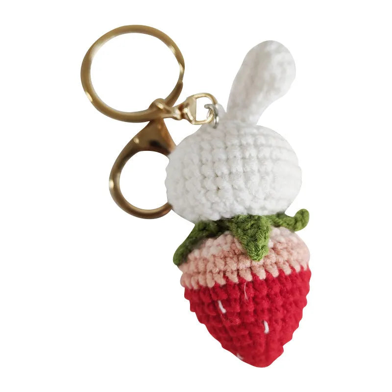 White hand-woven wire pendant with a cartoon rabbit and strawberry design, shown with its attachment key.