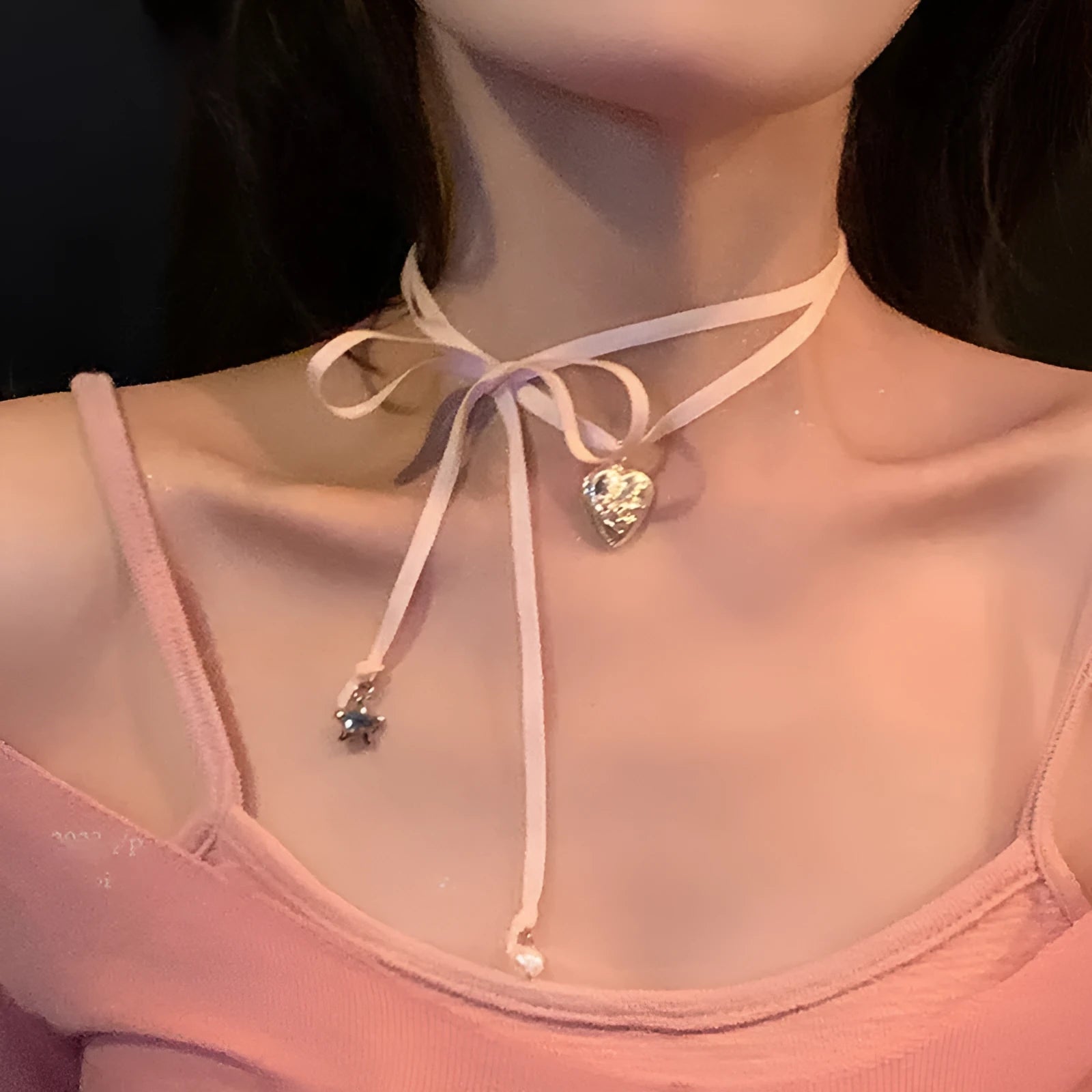 Close-up of a women's alloy fashion necklace with a love pendant and ribbon detail on a delicate clavicle chain.