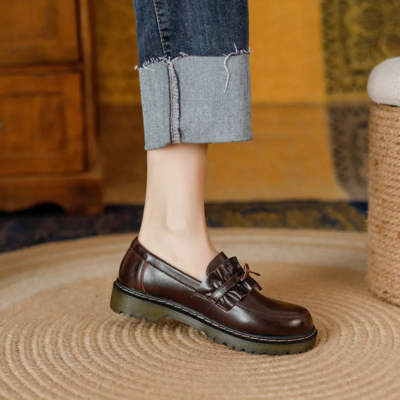 Black round-toe women's leather shoes with a chunky flat heel on a white background