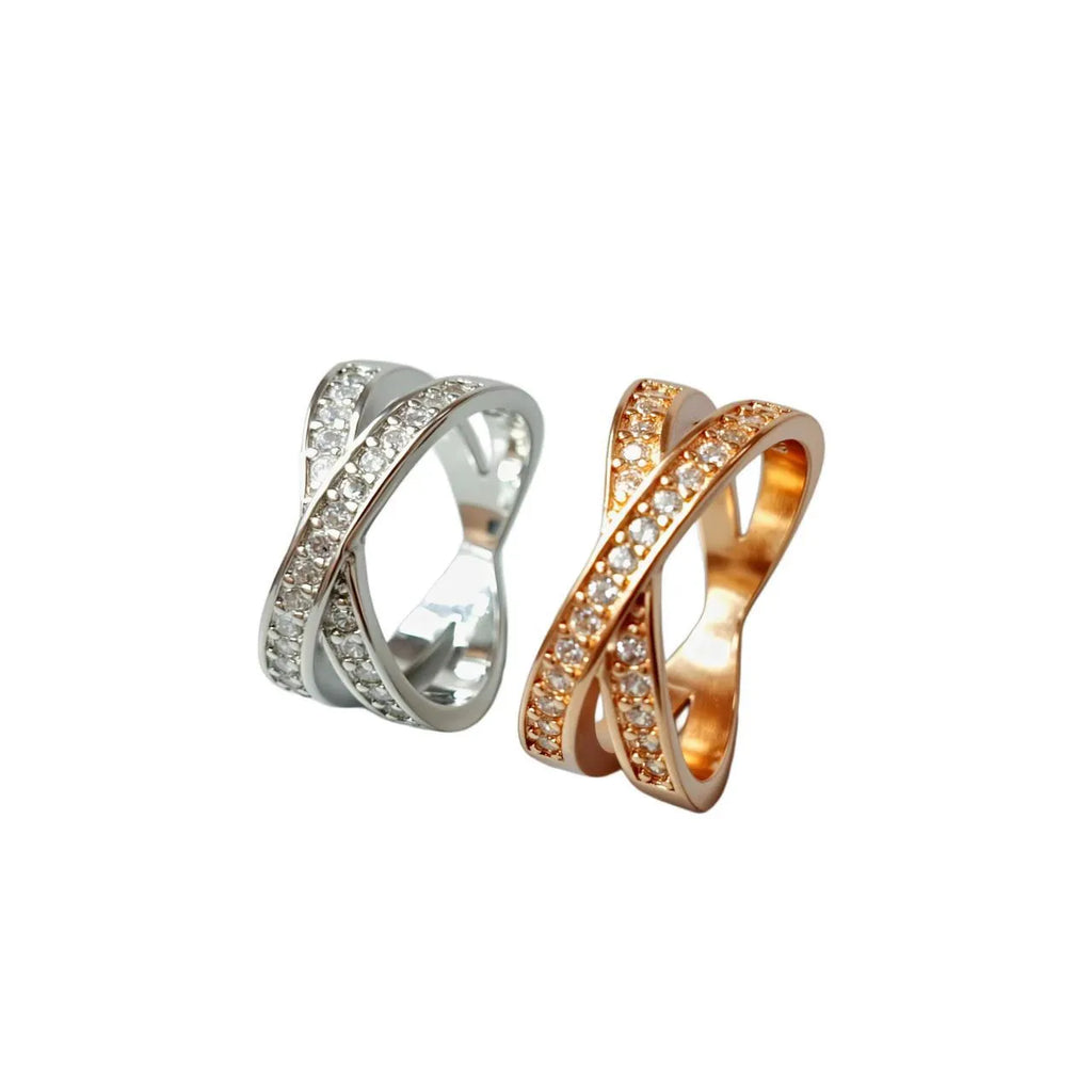 A silver or rose gold metal ring featuring a heart-shaped cross centrepiece with micro-inlaid zircon details.