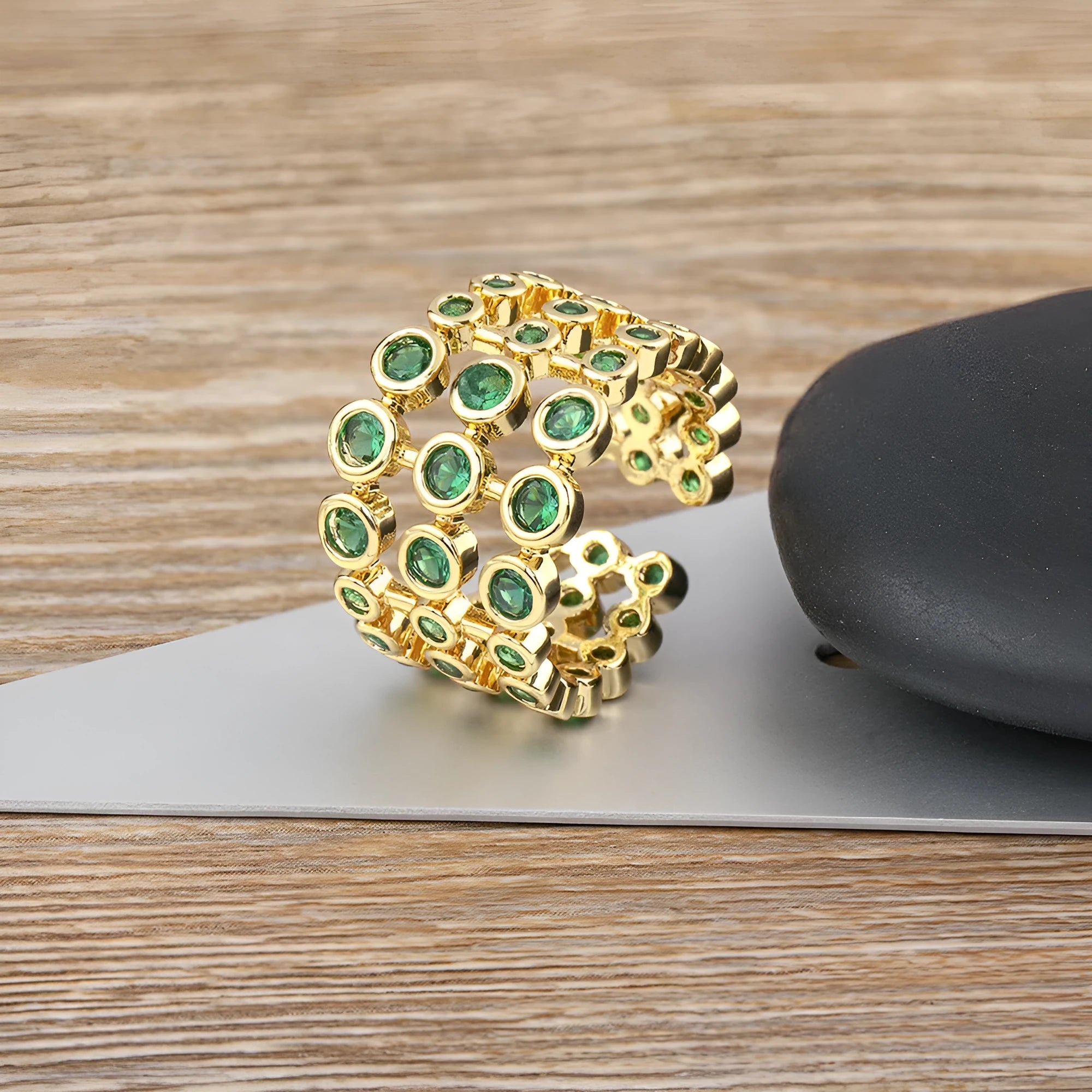 Copper ring with 18K gold plating and green zircon stones on a wide band.