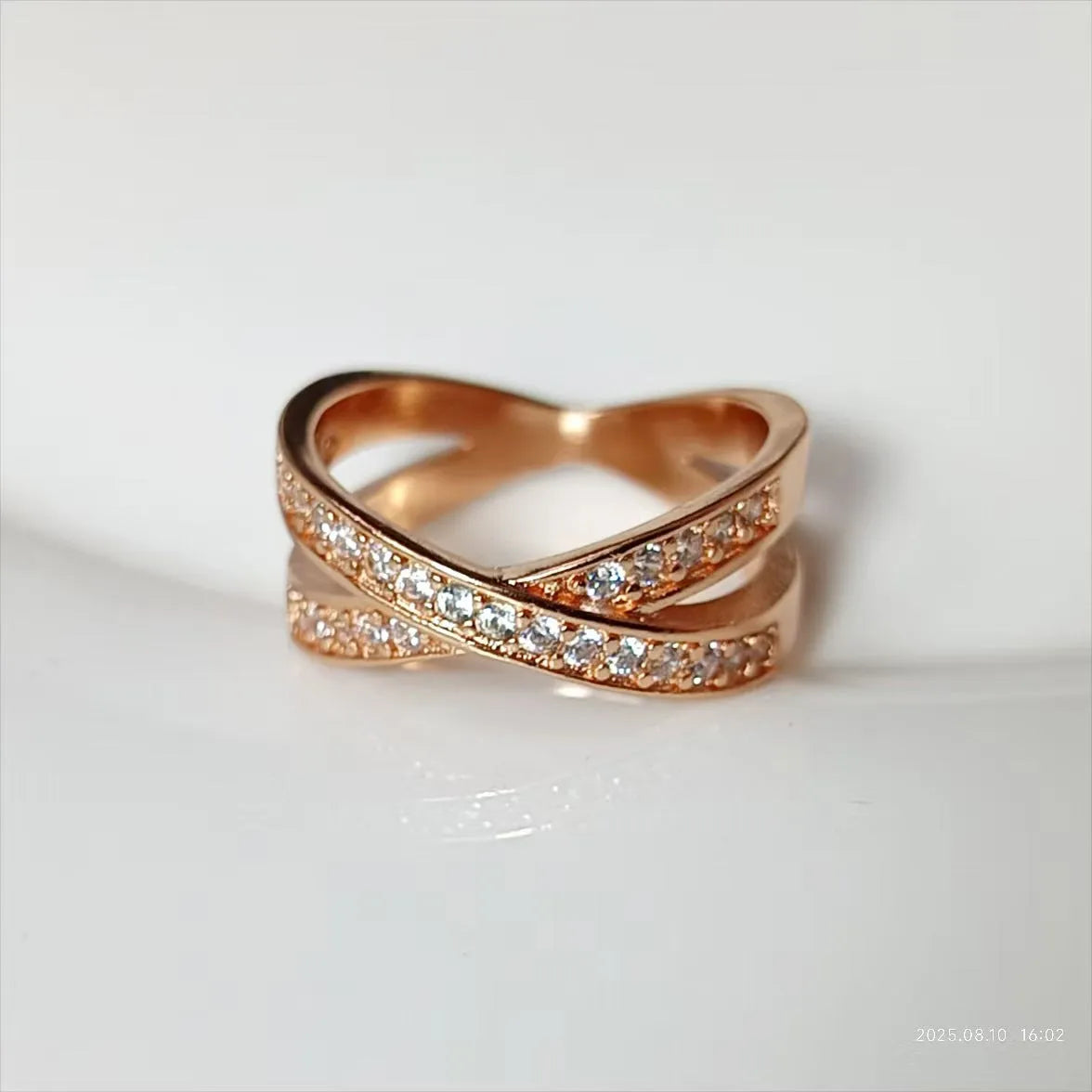 A silver or rose gold metal ring featuring a heart-shaped cross centrepiece with micro-inlaid zircon details.
