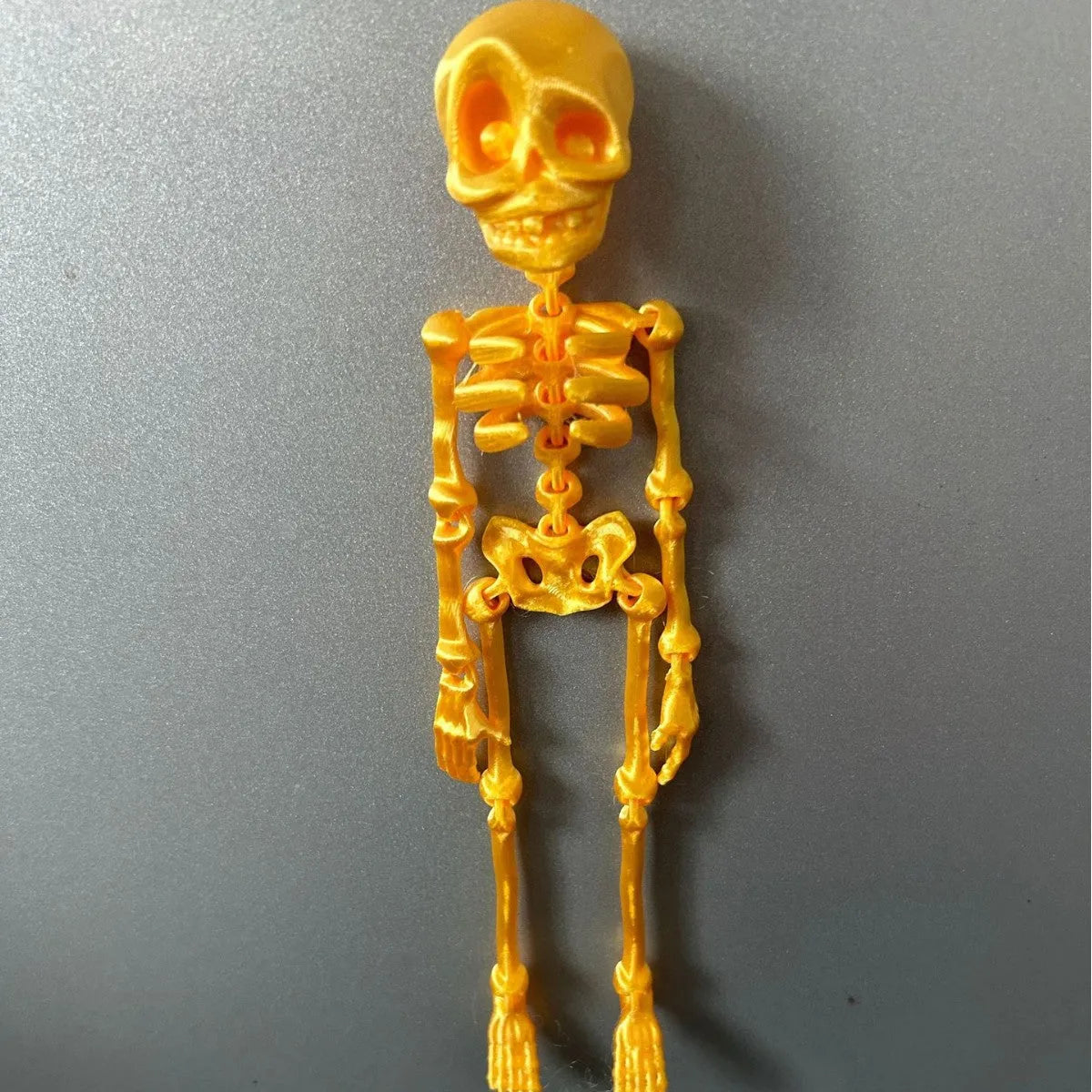 3D printed white skull refrigerator magnet with intricate details on a metallic surface.