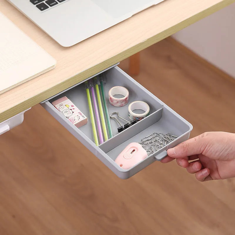 White plastic storage drawer with a cover and internal grid compartments, shown mounted underneath a wooden table.