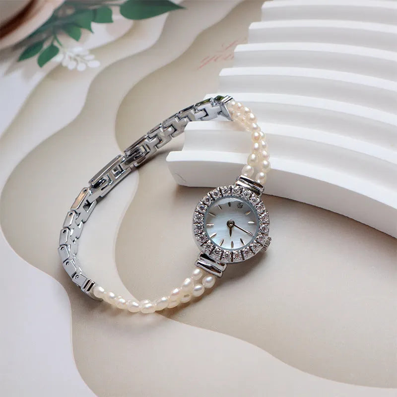 Light gold women's bracelet watch with freshwater pearls and an 18mm round dial on a stainless steel strap.