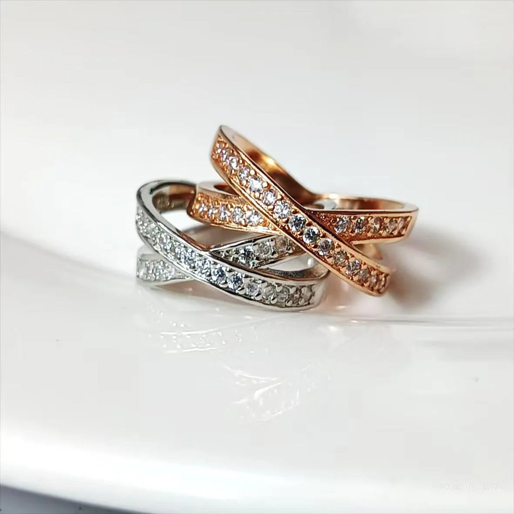 A silver or rose gold metal ring featuring a heart-shaped cross centrepiece with micro-inlaid zircon details.