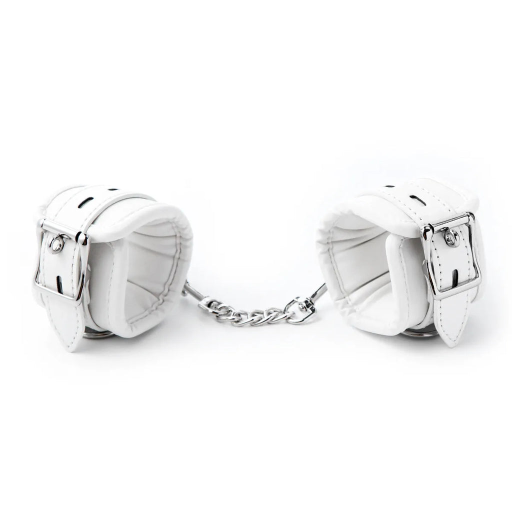 White PU sponge bondage set showing handcuffs, foot cuffs, and a neck cuff arranged together.