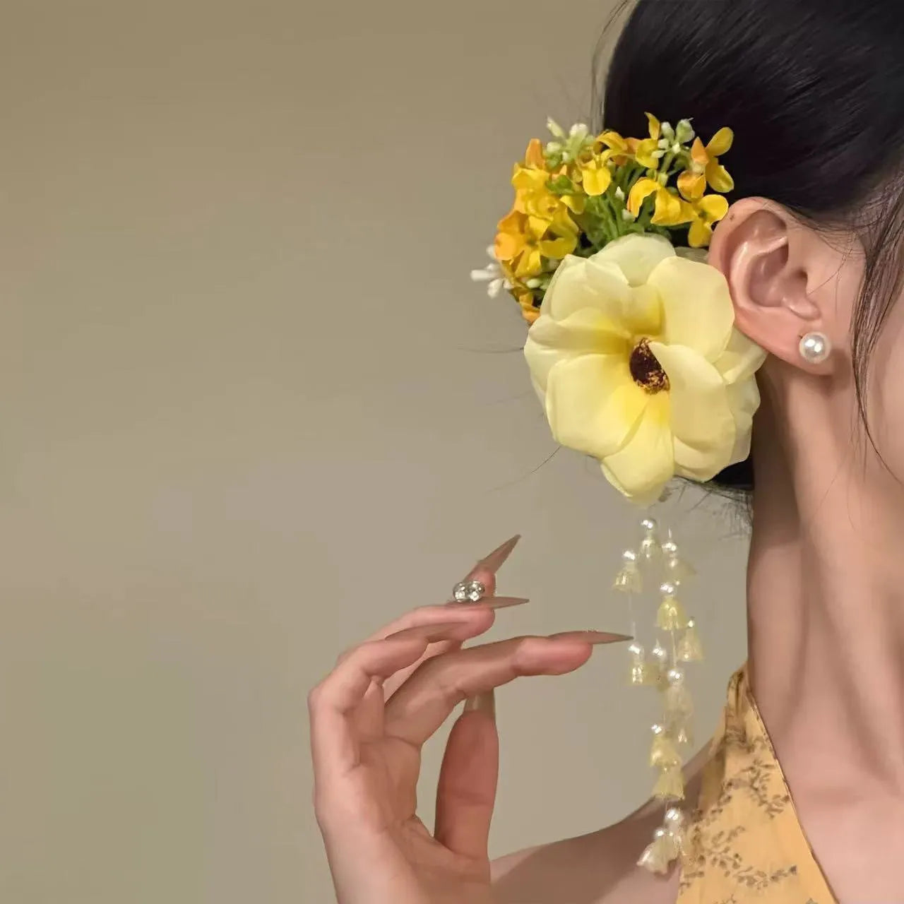 Handmade yellow and purple floral hair clip with pearl beads and long tassels on a metal side-clip.