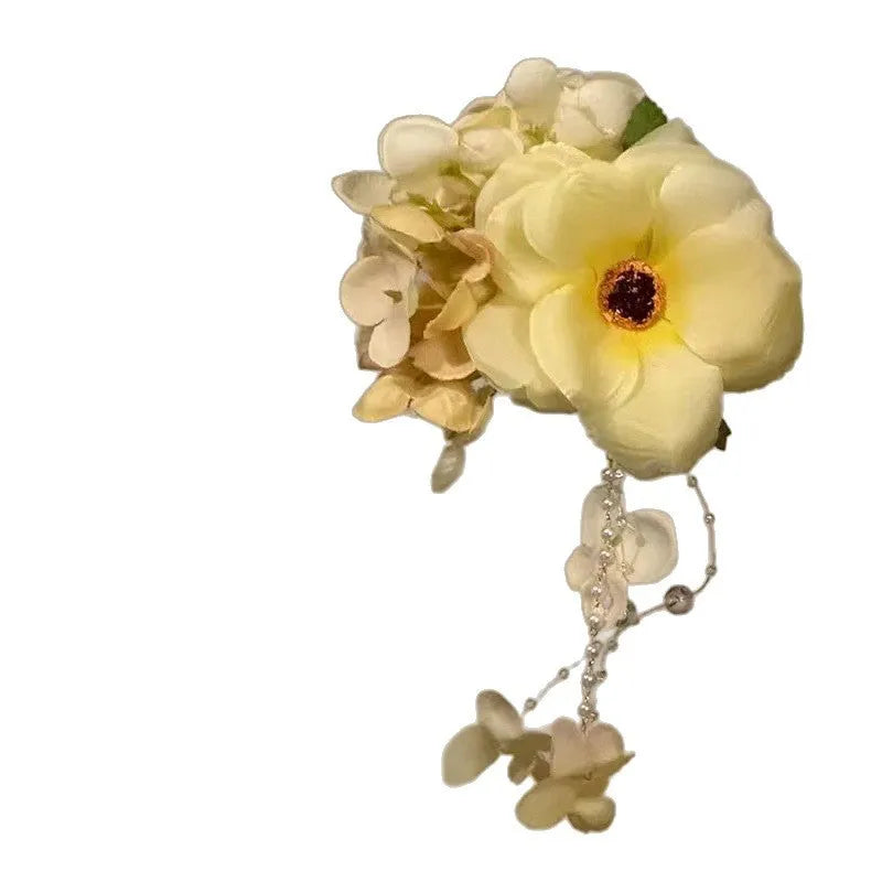Handmade yellow and purple floral hair clip with pearl beads and long tassels on a metal side-clip.