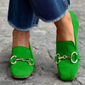 Green suede women's loafers with a round toe and metal buckle fastener on a flat rubber sole.