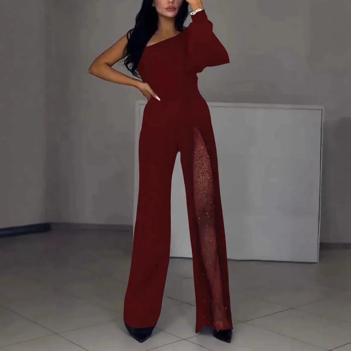 Black women's long sleeve jumpsuit with oblique shoulder neckline and high leg slit on a model.